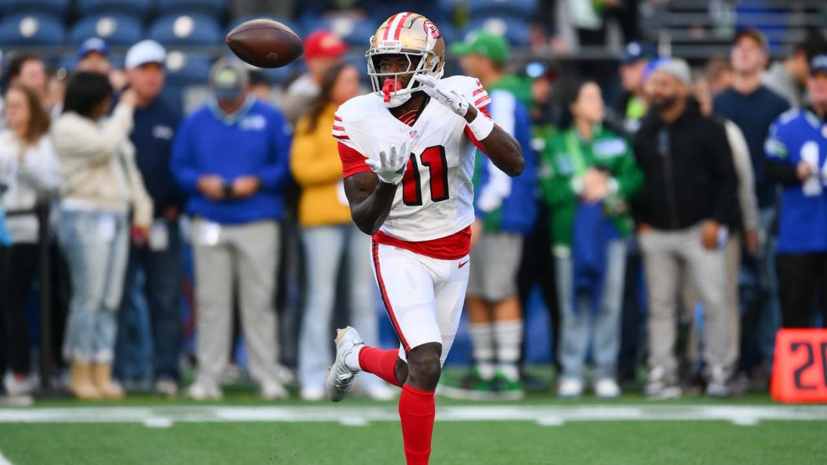San Francisco 49ers wide receiver Brandon Aiyuk catches a football during warmups at Lumen Field.