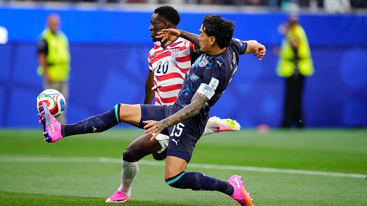 USMNT player competes for the ball against a player from the Paraguay national team
