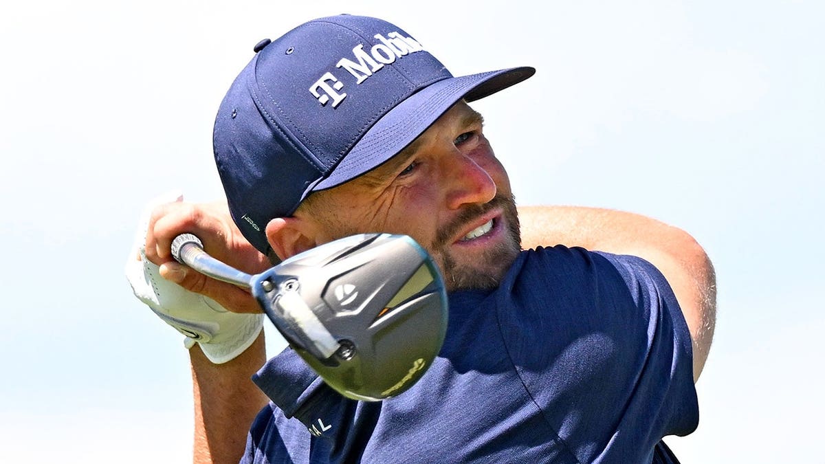 Wyndham Clark hitting a tee shot at the 18th hole during a golf tournament.