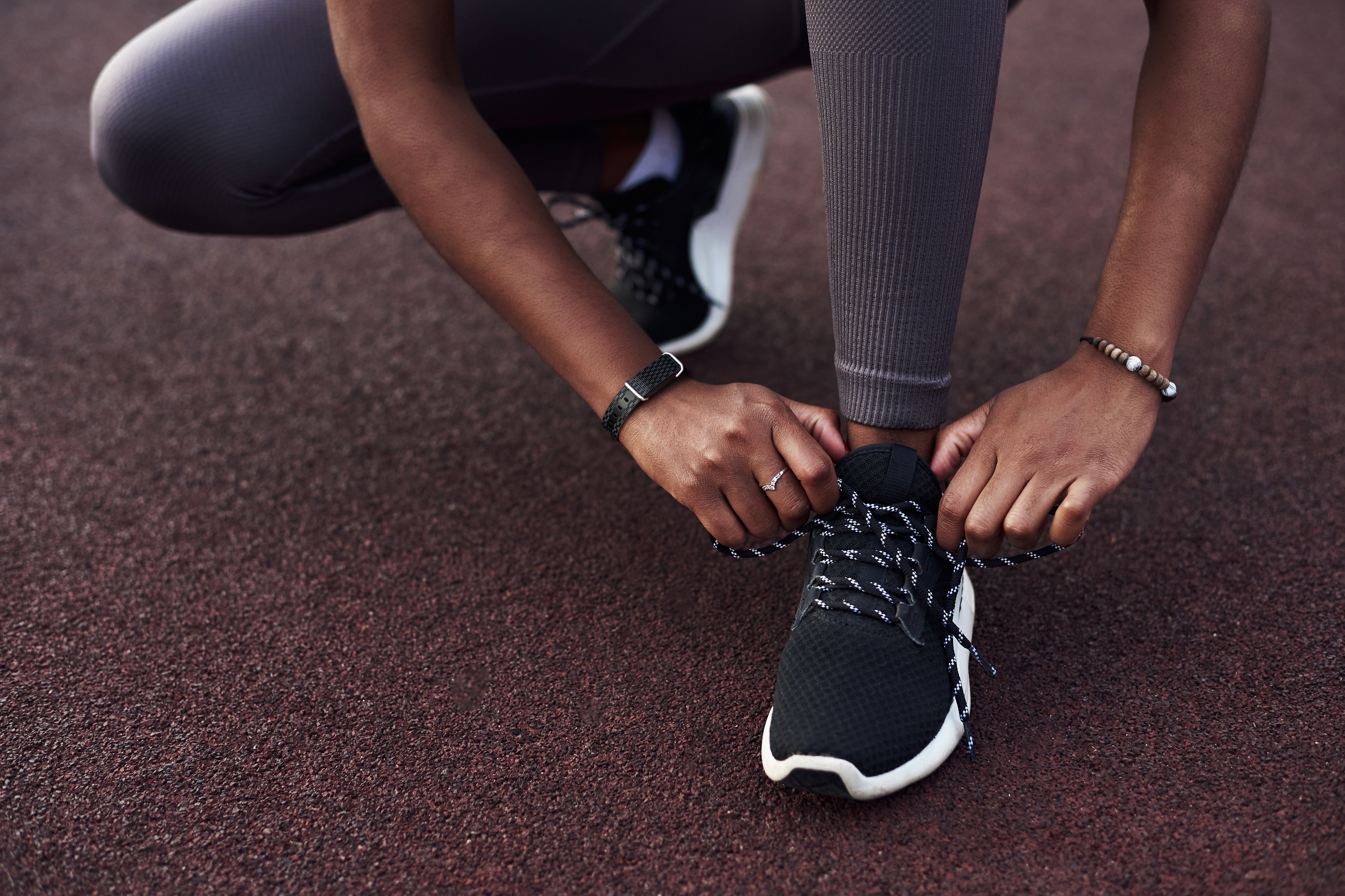 woman tying sneaker wearing a Hilo Core band on her wrist