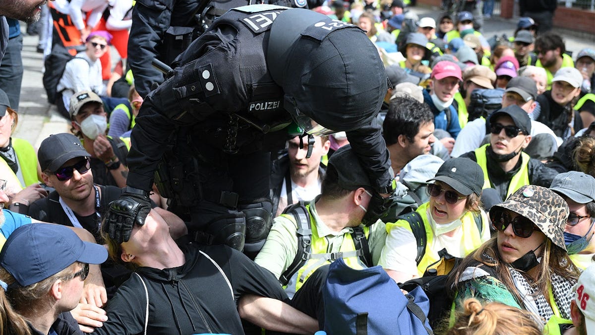 A policeman touches demonstrators sitting on a street near the Gothaer Square in Erfurt