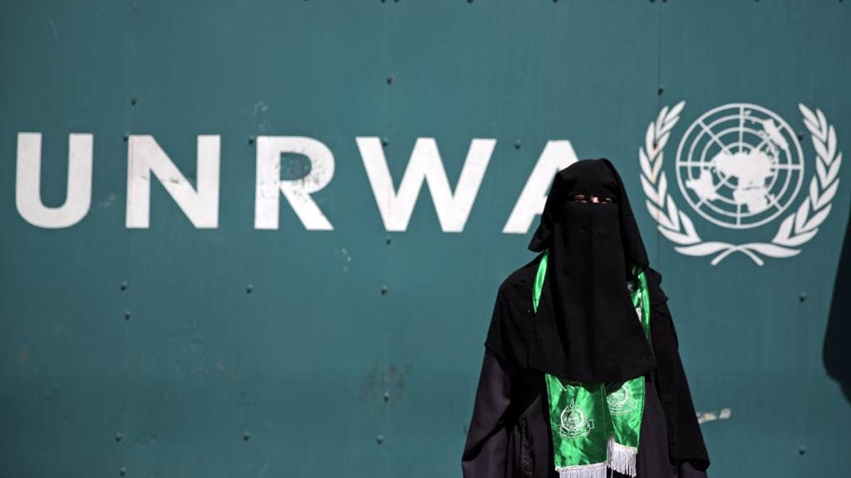 A Palestinian woman wears a green Hamas scarf attends a demonstration against a U.N. Relief and Works Agency (UNRWA) funding gap that could keep about 500,000 Palestinian students out of school this fall, outside the UNRWA Gaza Headquarters in Gaza City, Sunday, Aug. 16, 2015. The deputy chief of the UNRWA, which operates 700 schools, Sandra Mitchell, said that "if funding does not arrive" this month, the agency could delay the start of the school year. (AP Photo/Khalil Hamra)