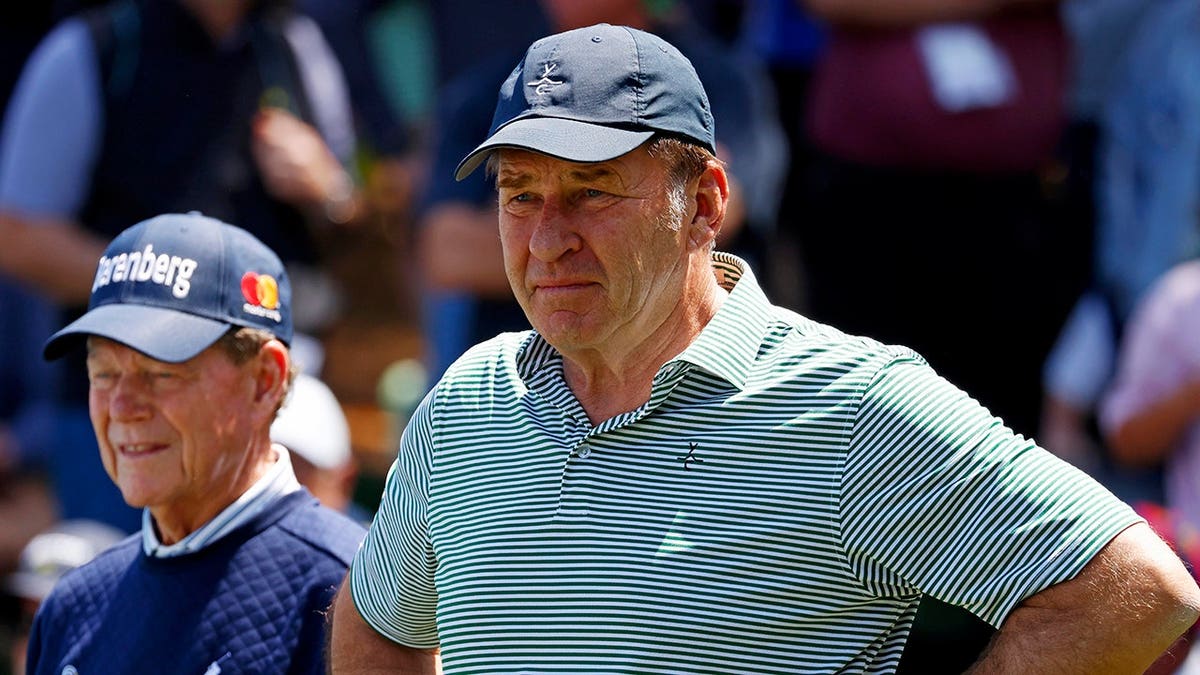 Tom Watson and Nick Faldo walk on the green at Augusta National Golf Club.