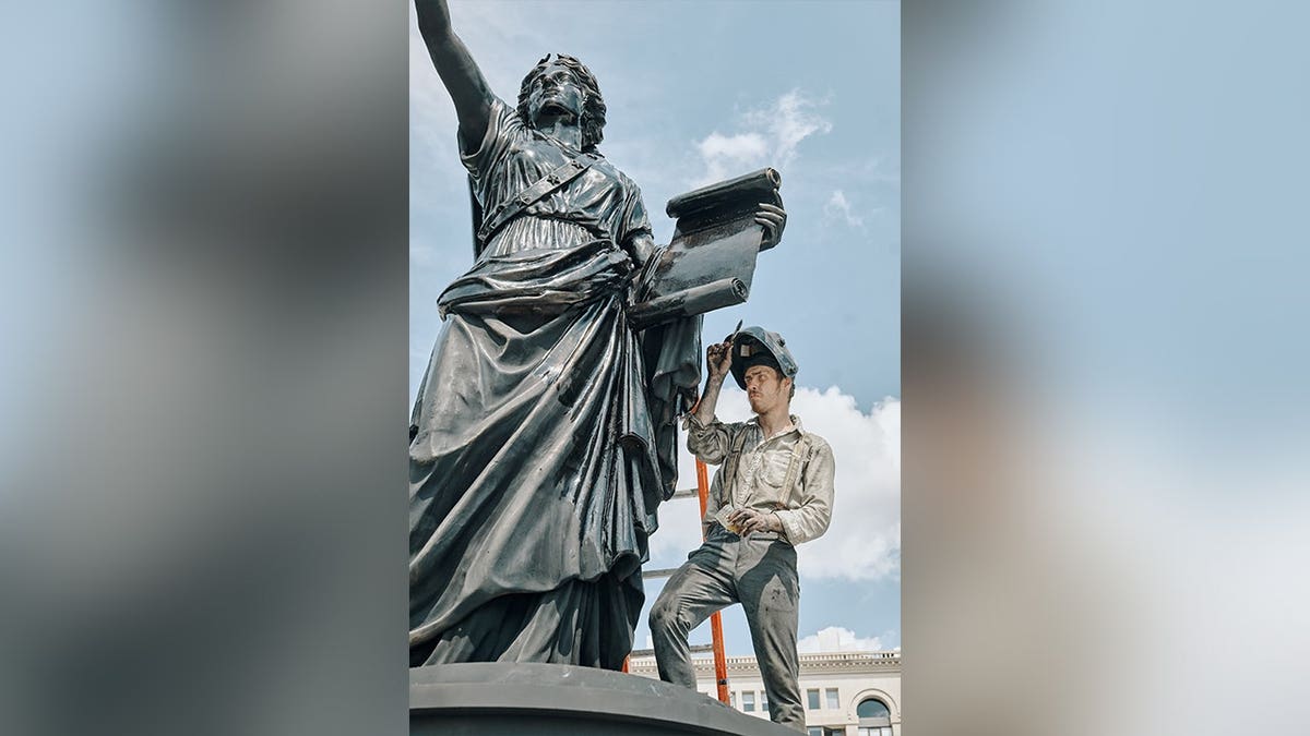 Worker finishing Spirit of Liberty statue at Freedom Plaza.