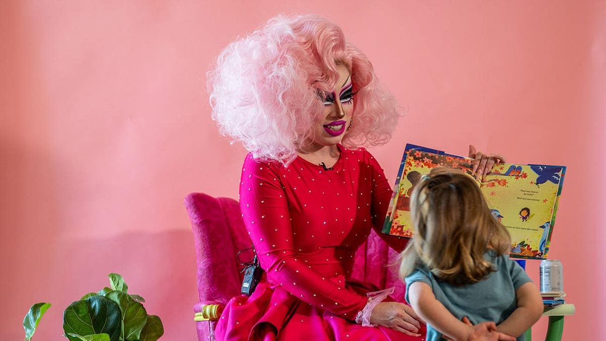 A drag queen reads from a children's book to young girl
