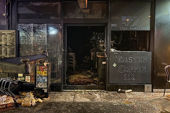 Loaves of bread and melted chairs sit out the front of the burnt cafe. 