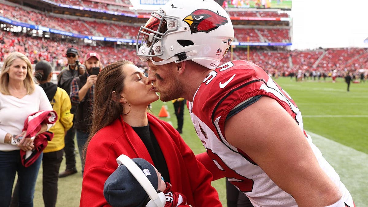 J.J. Watt kisses Kealia Watt as she holds Koa Watt at Levi's Stadium.