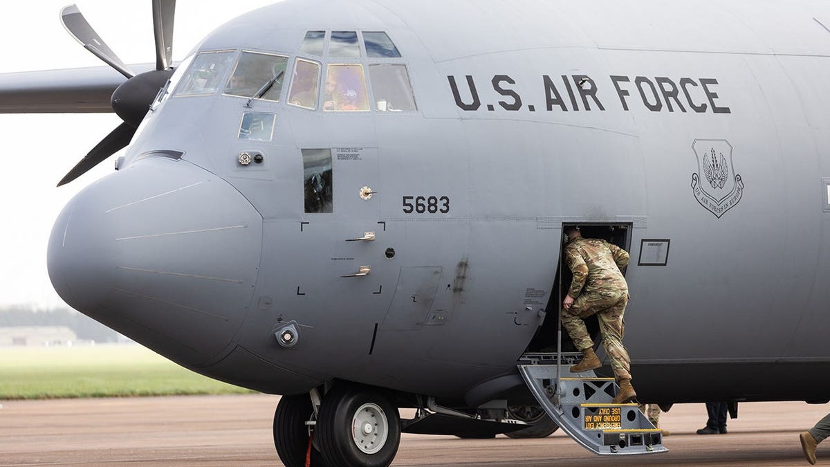 ground crew member entering aircraft on tarmac