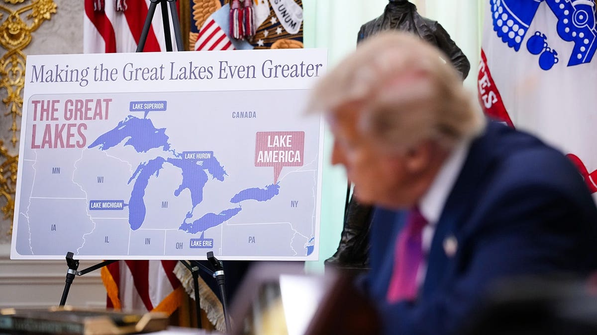 President Donald Trump signs an executive order as a map labeled Lake America is displayed.