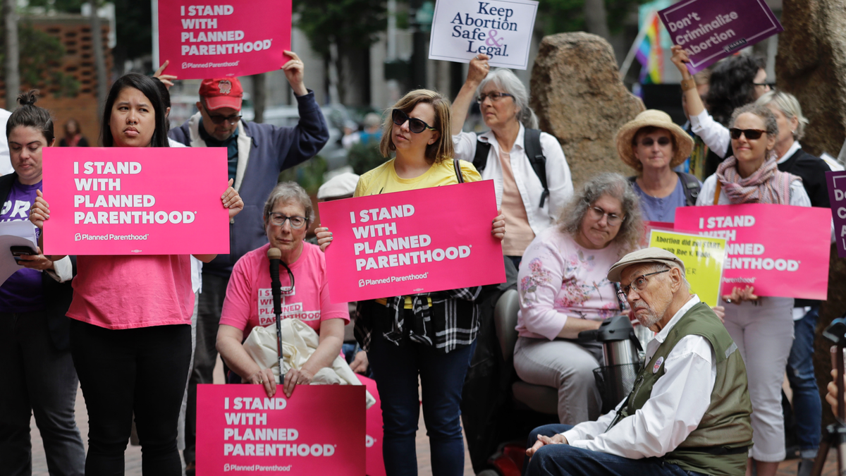 FILE - In this July 10, 2018 file photo, protesters hold signs supporting Planned Parenthood in Seattle, as they demonstrate against President Donald Trump and his choice of federal appeals Judge Brett Kavanaugh as his second nominee to the Supreme Court. On Tuesday, March 5, 2019, the American Medical Association and Planned Parenthood jointly filed a federal court lawsuit challenging a new Trump administration rule for family-planning grants which had been sought by anti-abortion activists. (AP Photo/Ted S. Warren, File)