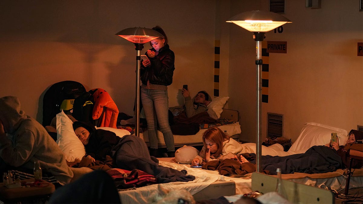People lie on mattresses in the underground parking lot of a hotel that has been turned into a bomb shelter during an air raid alert in Kyiv, Ukraine, Sunday, Feb. 27, 2022. Terrified men, women and children sought safety inside and underground, and the government maintained a 39-hour curfew to keep people off the streets as more than 150,000 Ukrainians fled to neighboring countries and the United Nations warned the number could grow to 4 million if fighting escalates.