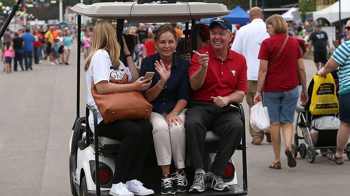 Lindsey Graham rides on a golf cart with Darline Graham Nordone at the Iowa State Fair.