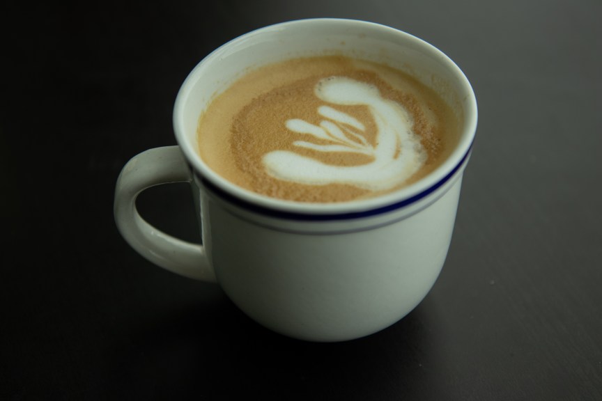 An espresso in a white ceramic cup, with milk foam in the shape of a tulip on top.