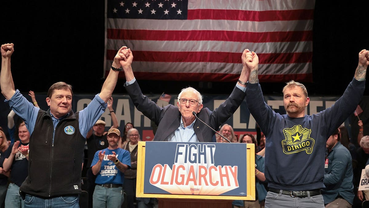 Bernie Sanders standing with Troy Jackson and Graham Platner on a stage.