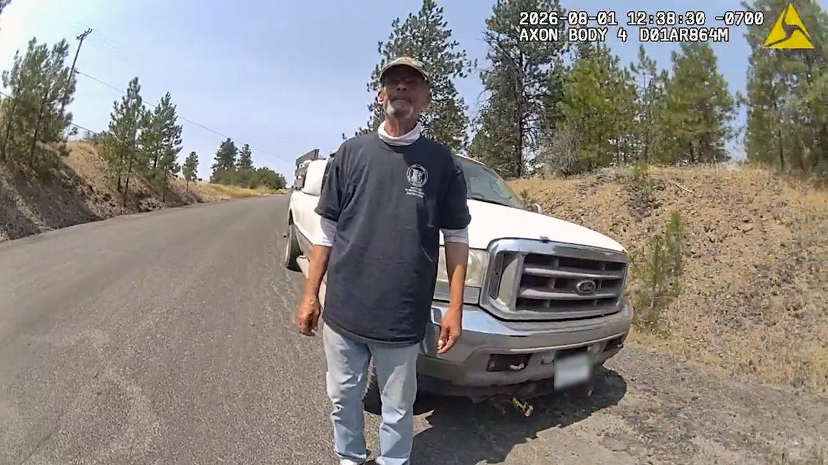 Airway Heights police body-camera view of thick smoke rising behind a dry field, trailer and parked vehicle.