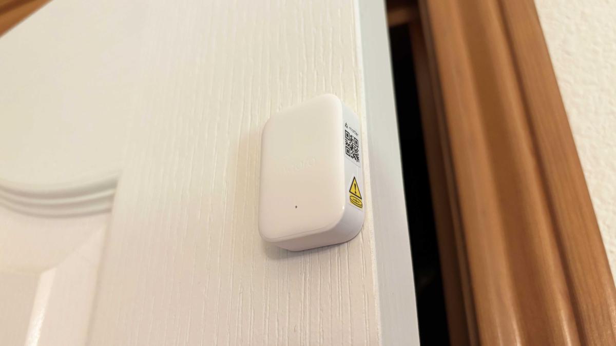 Aqara's P100 sensor on the edge of a white door.