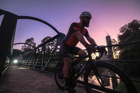 Cyclists cross the Parramatta river in Parramatta Park at sunrise.