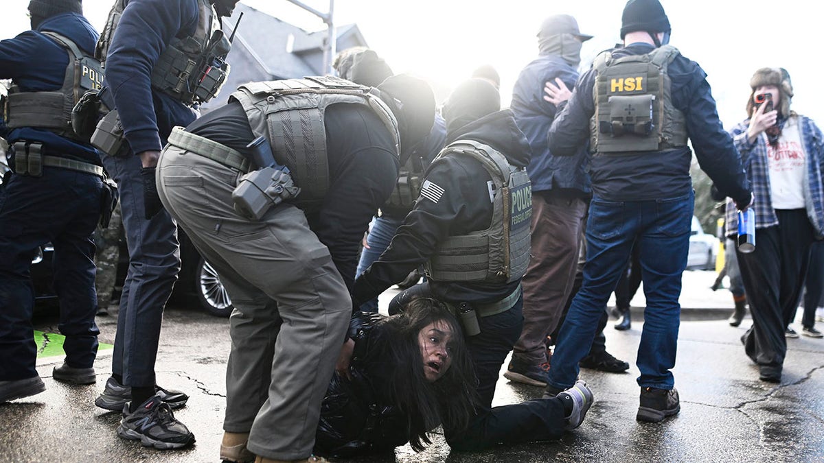 ICE agents detain a woman after pulling her from a car before on January 13, 2026 in Minneapolis, Minnesota. The Trump administration has deployed over 2,400 Department of Homeland Security agents to the state of Minnesota in a push to apprehend undocumented immigrants.