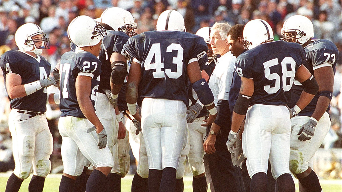 Jerry Sandusky speaks with Penn State players on the field during his time as the Nittany Lions' defensive coordinator