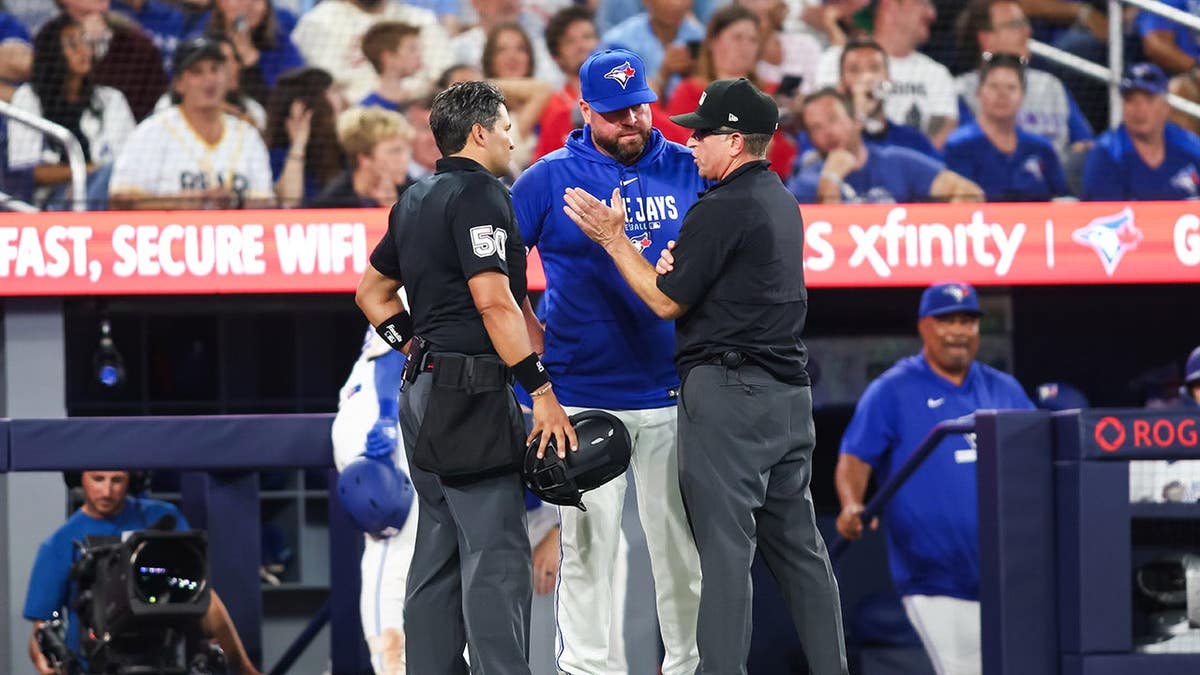 John Schneider stands with umpires during a rule review at Rogers Centre.