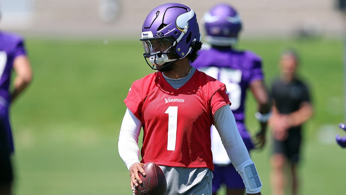 Kyler Murray wearing number 1 jersey participating in a drill at a football practice.