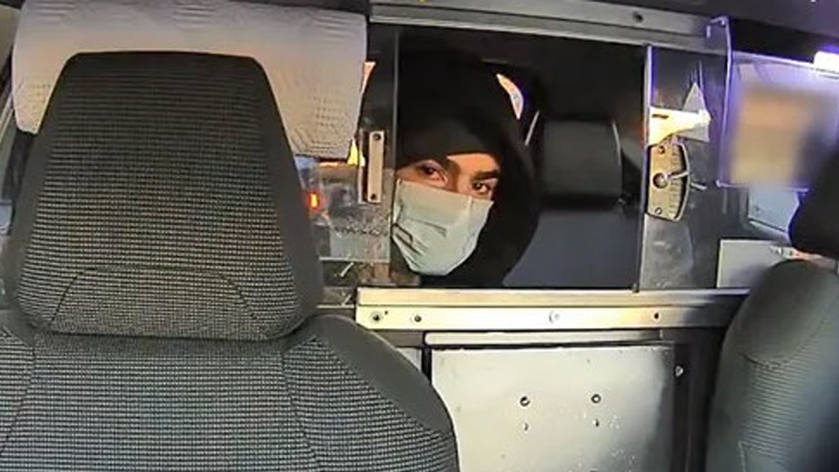 a masked man alleged to be luigi mangione sitting in a taxi backseat in nyc