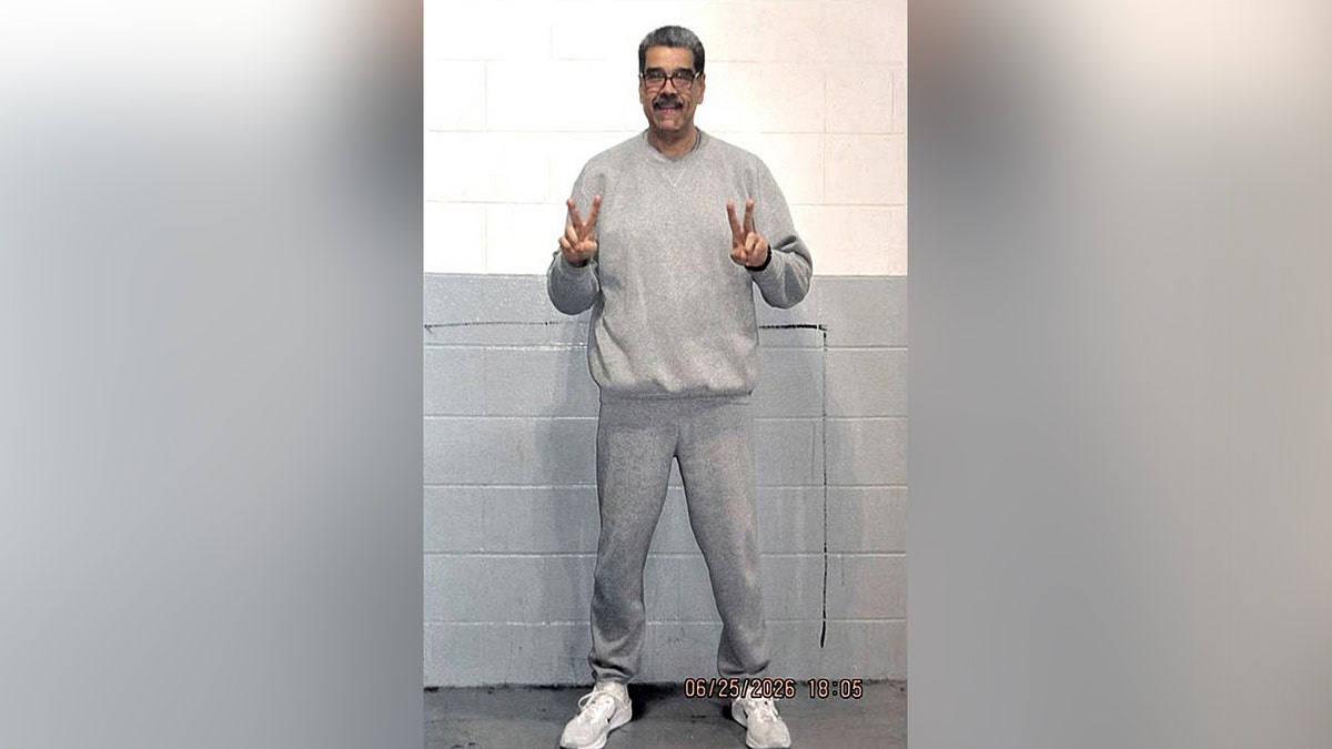nicolas maduro in gray sweatsuit holding two peace signs and smiling