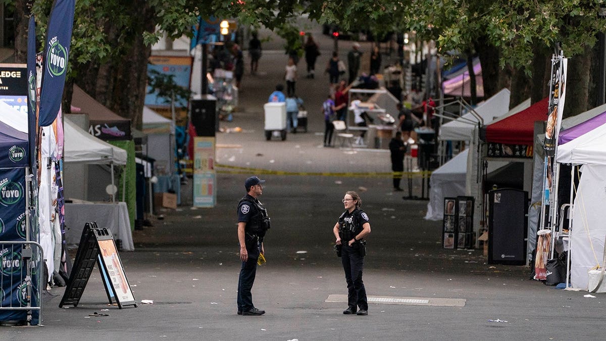 Police officers keep watch at a mass shooting scene at the Bite of Seattle food festival.