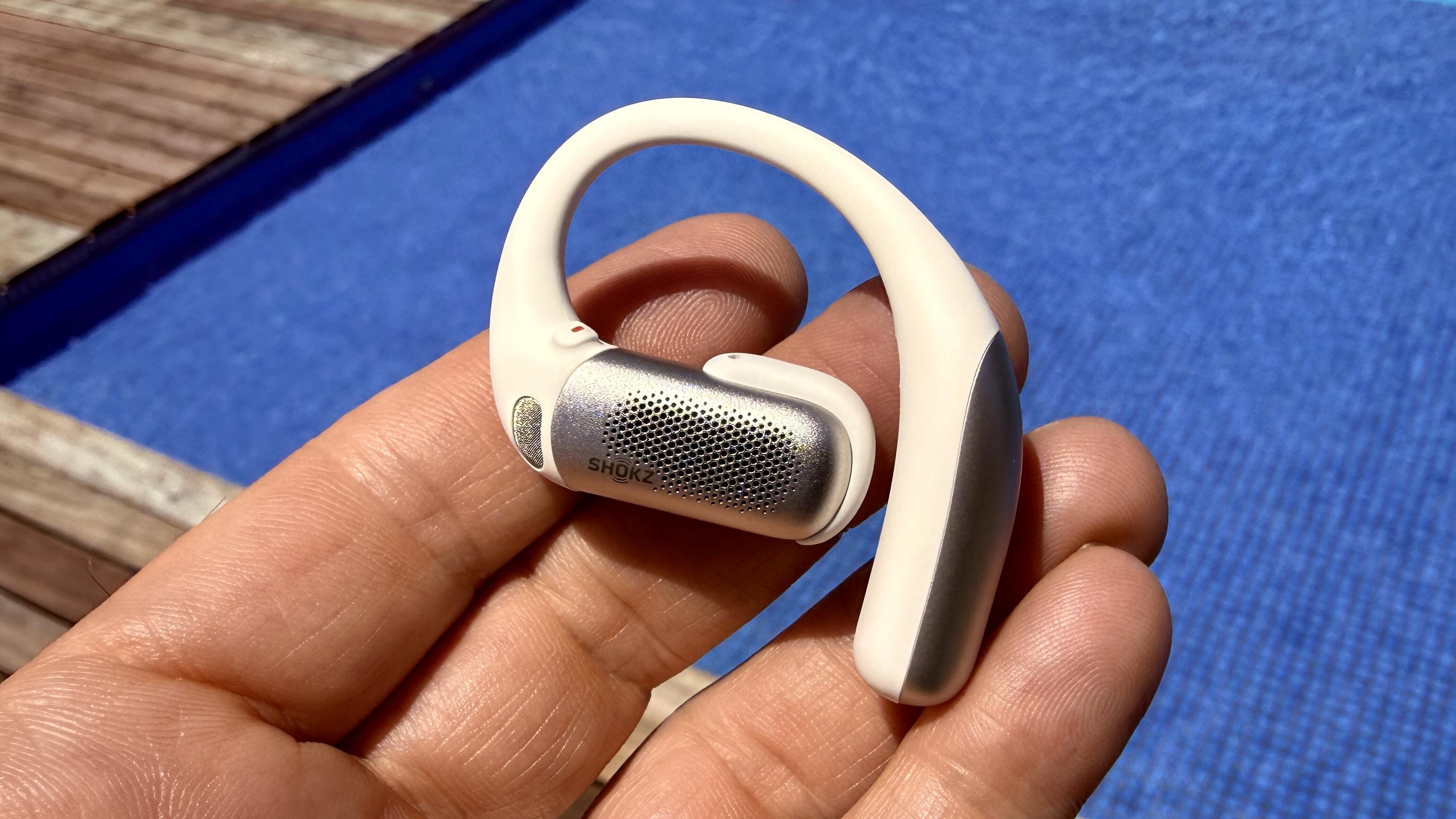 Shokz OpenFit Pro earbuds in hand displaying their controls