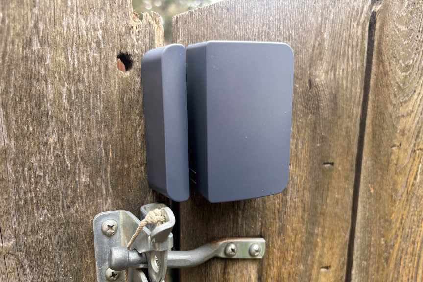 Abode's outdoor sensor close up on a wood gate.