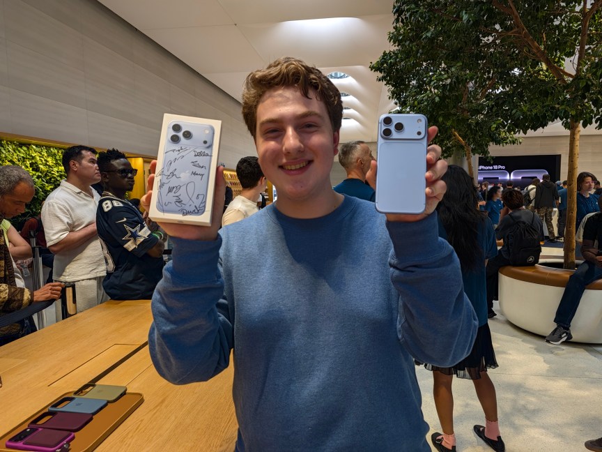 Dallen Frutchey holds up iPhone 18 Pro Max and signed box.