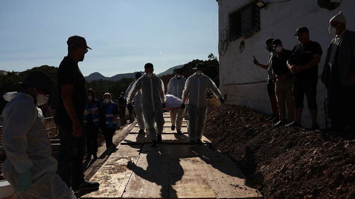 Workers carry the body of a migrant who died while trying to cross into Ceuta