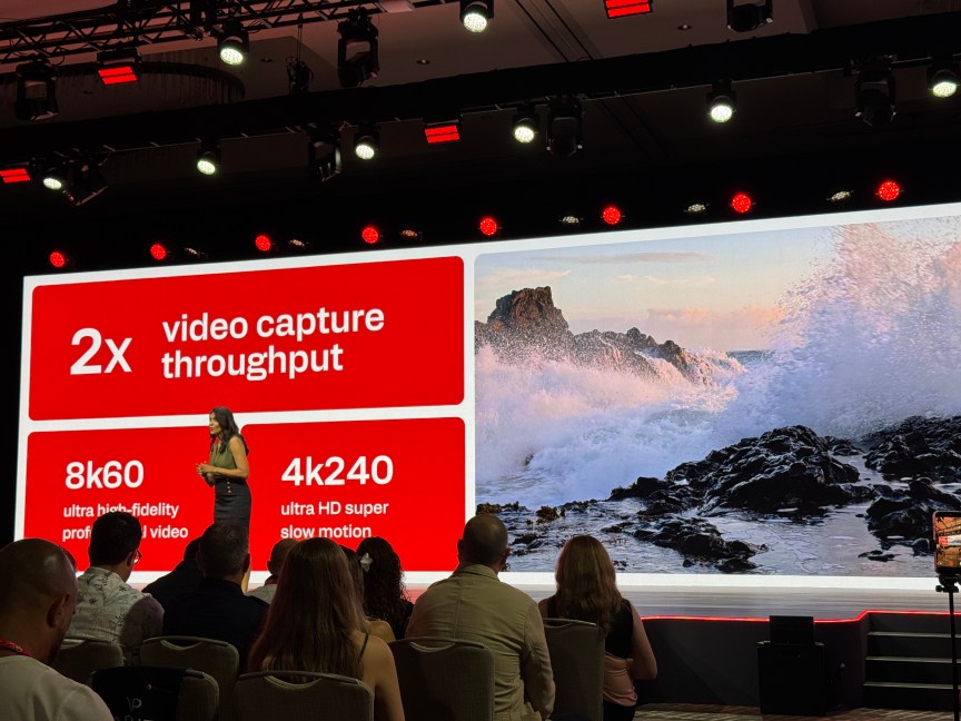 Woman on stage in front of video slide