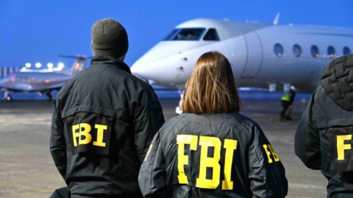 FBI agents stand on the tarmac as a plane arrives carrying Zobaidul Amin following his extradition from Malaysia to face federal charges in Alaska.