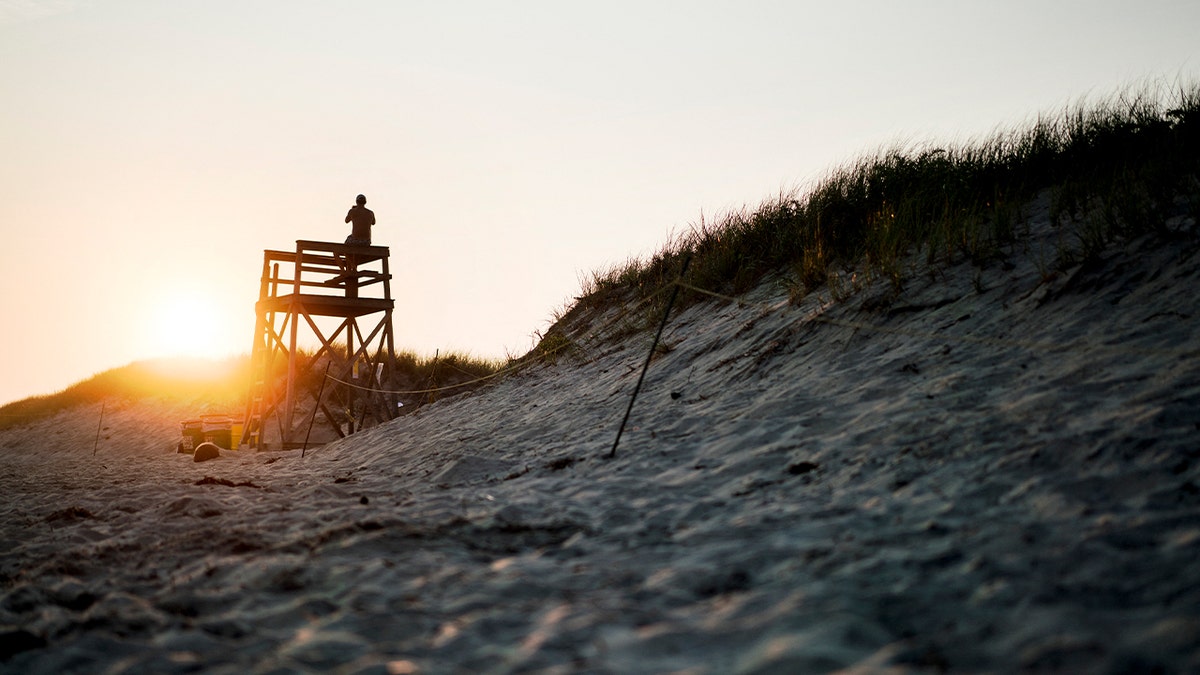 lifeguard watching beach from tower post at beach during sunset