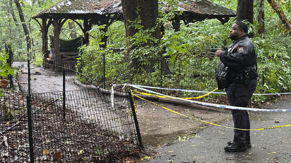 An NYPD officer stands near police tape outside a wooden gazebo in Central Park