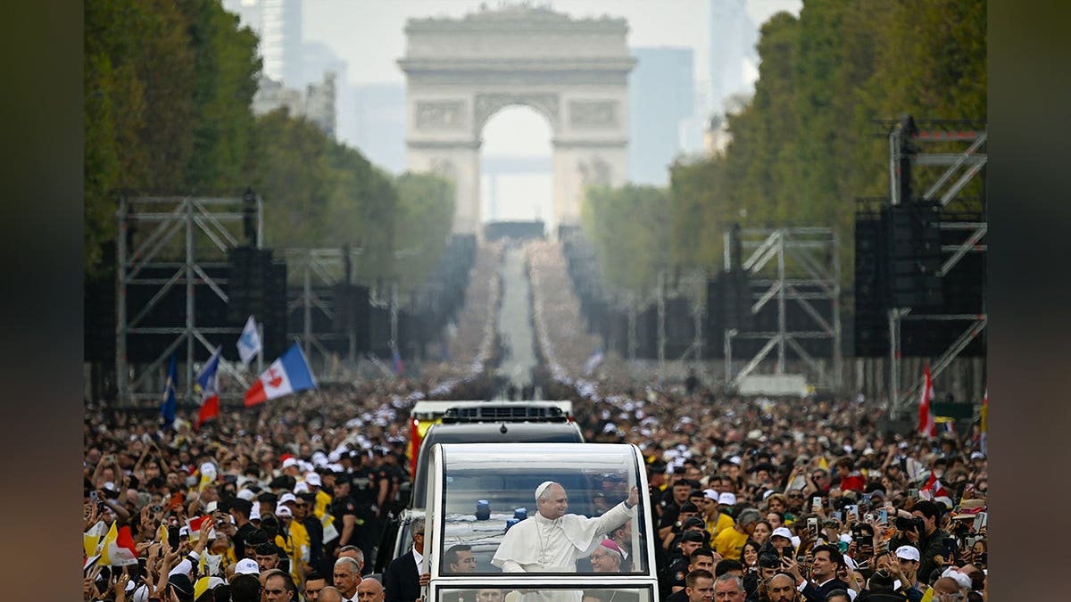 Pope Leo XIV waves from the popemobile as he arrives at Place de la Concorde in Paris.
