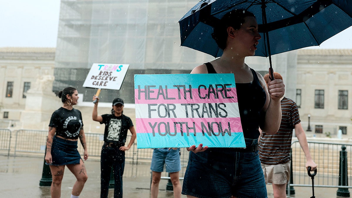 A protester holds a sign in support of sex changes for transgender children outside the U.S. Supreme Court Building in Washington, DC, on June 18, 2025.
