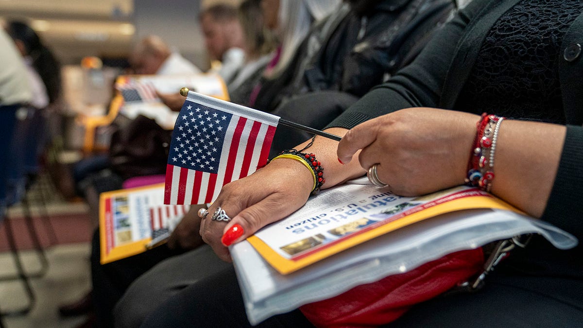 A woman holds an American flag at a citizenship ceremony.